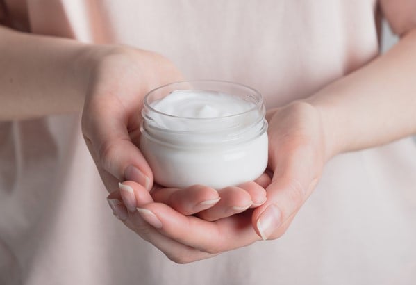 woman holding a container of moisturizer
