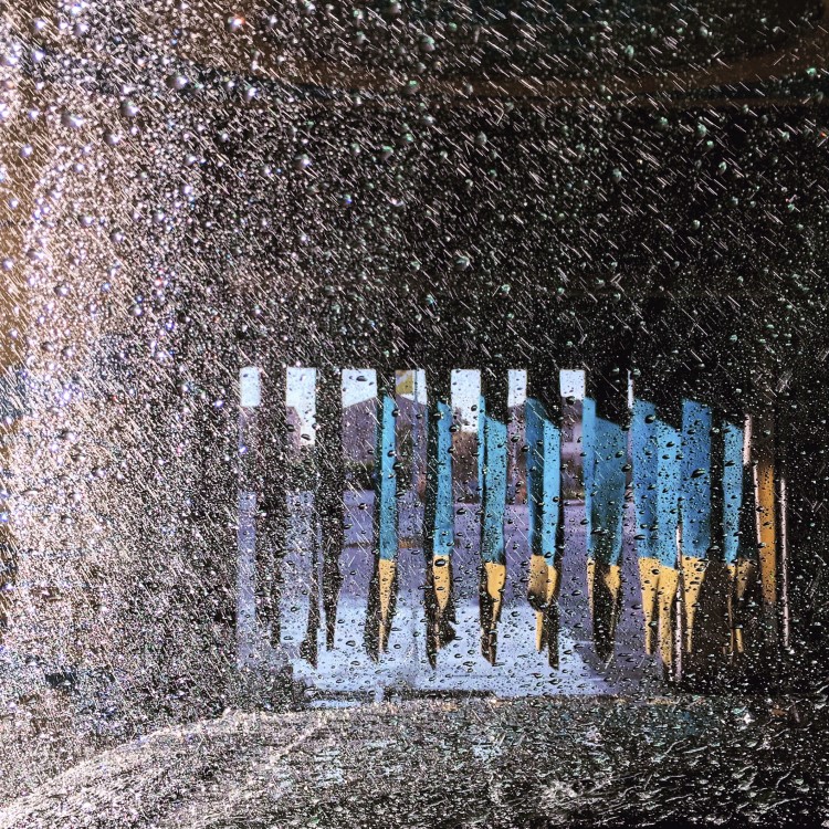 going through a tunnel car wash conveyor as the vehicle is rinsed and dried