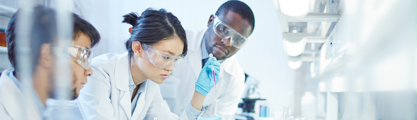 scientists wearing white coats and goggles working in a lab