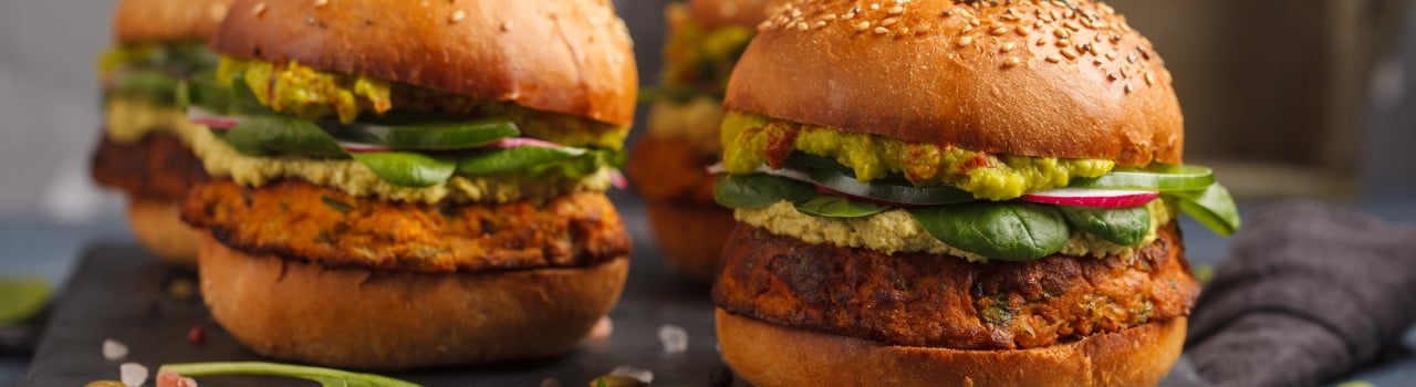 Plant-based meat burgers topped with lettuce and avacado. 