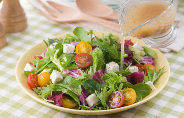 bowl of salad with dressing being drizzled on