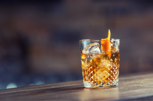 whiskey glass filled with whiskey and an orange garnish