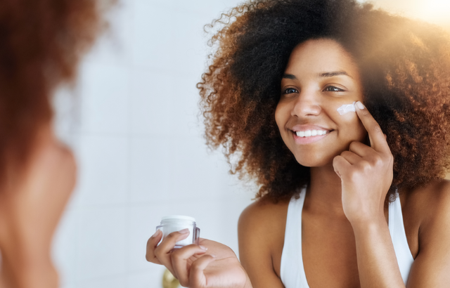 woman applying skin moisturizer to her cheek